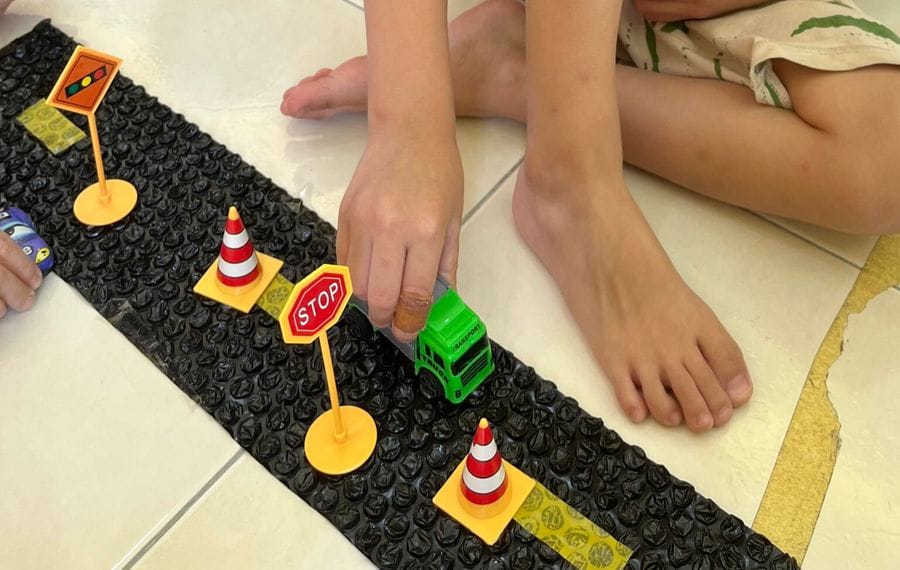 A toddler playing with a toy truck on a road safety mat